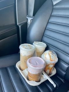 two cups of coffee sit on a tray in the back seat of a car