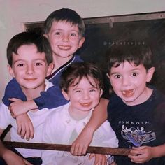 three boys are posing for a picture with their arms around each other and one boy is holding a baseball bat