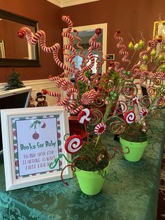 candy canes are displayed in green pots on a table