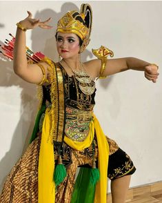 a woman dressed in an elaborately designed costume and headdress, dancing with her arms outstretched