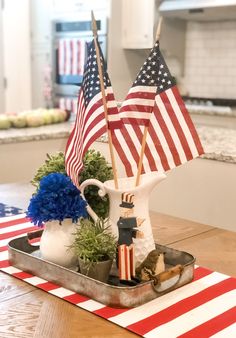 an american flag decoration on a tray with flowers and flags in the centerpieces