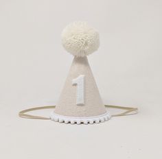 a white hat with a number one on it and pom - poms around the top