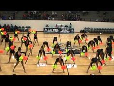 a group of cheerleaders performing on a basketball court with neon colored pom poms