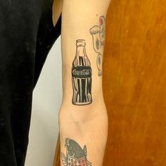 a person with a tattoo on their arm holding a bottle and fish in the other hand