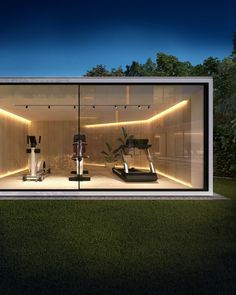 the inside of a glass building with treadmills and exercise equipment in it at night