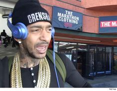 a man with headphones on standing in front of a store wearing a beanie