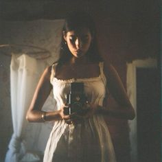 a woman in a white dress holding a camera