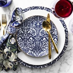 a table setting with blue and white plates, silverware and wine glasses on it