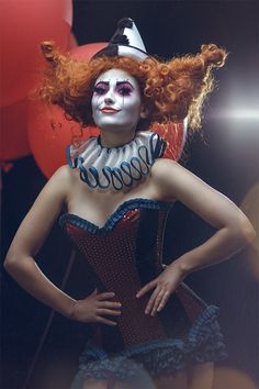 a woman with red hair and makeup is dressed as a clown in front of balloons