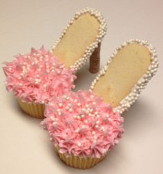 two cupcakes with pink and white frosting on them, one is shaped like a pair of shoes