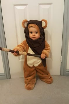 a baby dressed in a bear costume holding a baseball bat