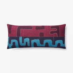 a red and blue pillow sitting on top of a white wall