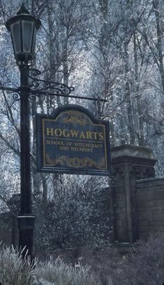 a sign for hogwart's in front of a light pole and some trees