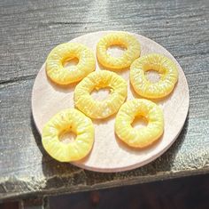 four pieces of pineapple sitting on top of a white plate next to a wooden table