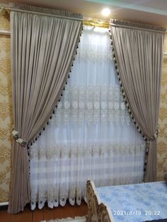 the curtains are hanging in front of the window with white lace on them, and there is a bed next to it