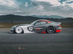 a car that is sitting in the middle of an asphalt lot with mountains in the background