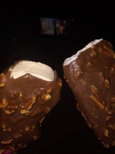 two pieces of chocolate covered ice cream on top of each other in front of a dark background