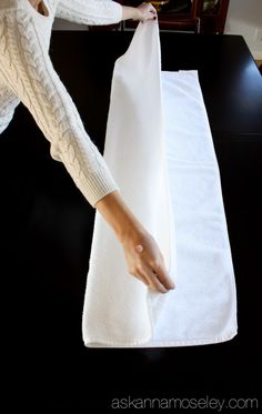 a woman is making a white towel on top of a black table with her hands