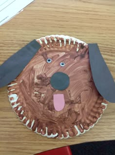 a paper plate with a dog face on it sitting on top of a wooden table