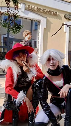 two women dressed in costumes sitting on a bench