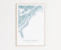 a framed poster with the words east coast in blue and white, against a white wall