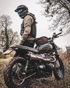 a man standing next to a motorcycle in the grass and looking at something behind him