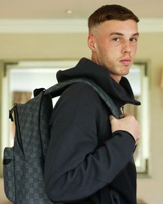 a man with a backpack on his back is looking at the camera while standing in front of a mirror