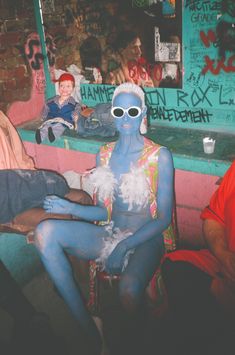 a man with blue paint on his body sitting in front of a counter