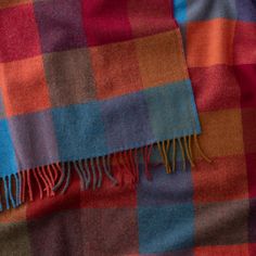 an orange, blue and red plaid blanket with fringes on it's edges