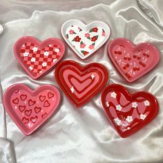 six heart shaped dishes sitting on top of a white cloth