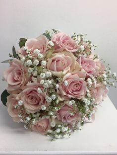 a bouquet of pink roses and baby's breath flowers on a white countertop