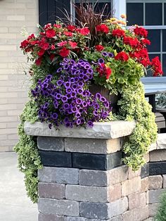 colorful flowers are growing in a brick planter