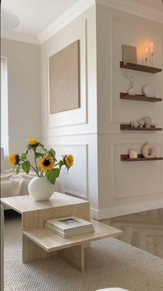 a living room with white furniture and sunflowers in the vase on the coffee table