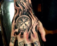 a hand with an octopus and compass tattoo on it