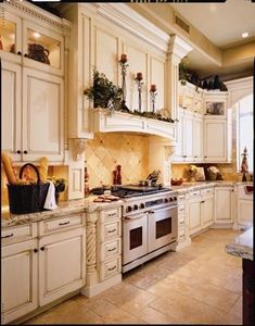 a large kitchen with white cabinets and marble counter tops on the island in front of an oven