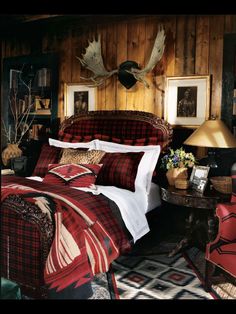 a bed with red and black plaid comforter next to a lamp on a table