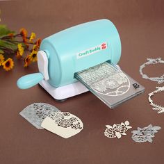 a stamper and some cut outs on a table with flowers in the back ground