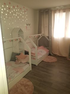 two white bunk beds sitting next to each other on top of a hard wood floor