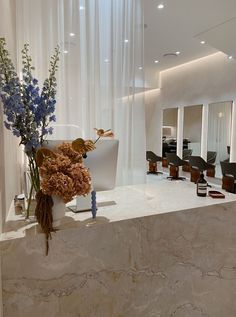 a vase filled with flowers sitting on top of a counter next to a chair and window