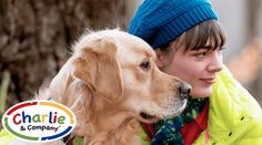 a woman is hugging her dog in front of a tree with the name charlie and company on it