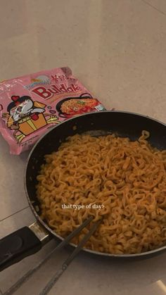 a pan filled with noodles next to a bag of ramen