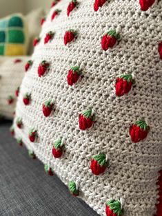 a crocheted pillow with red strawberries on it