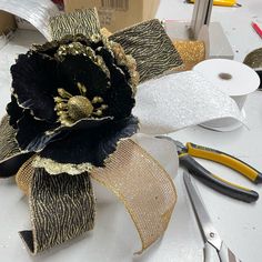 a black and gold flower sitting on top of a table next to some tape measure