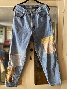 an old pair of jeans with patches on them hanging from a door hanger in front of a mirror