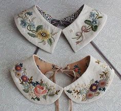 four pieces of embroidered fabric with flowers and leaves on them sitting on a white tablecloth