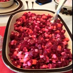 a bowl full of chopped beets and carrots on a table with utensils