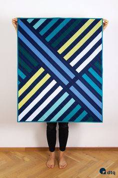 a person holding up a blue and yellow quilt