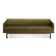 a green couch sitting on top of a white floor next to a wooden frame and armrest