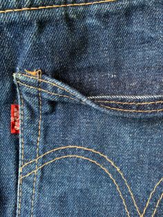 the back pocket of a pair of blue jeans with yellow stitching on each side