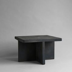 a black square table sitting on top of a white floor next to a gray wall